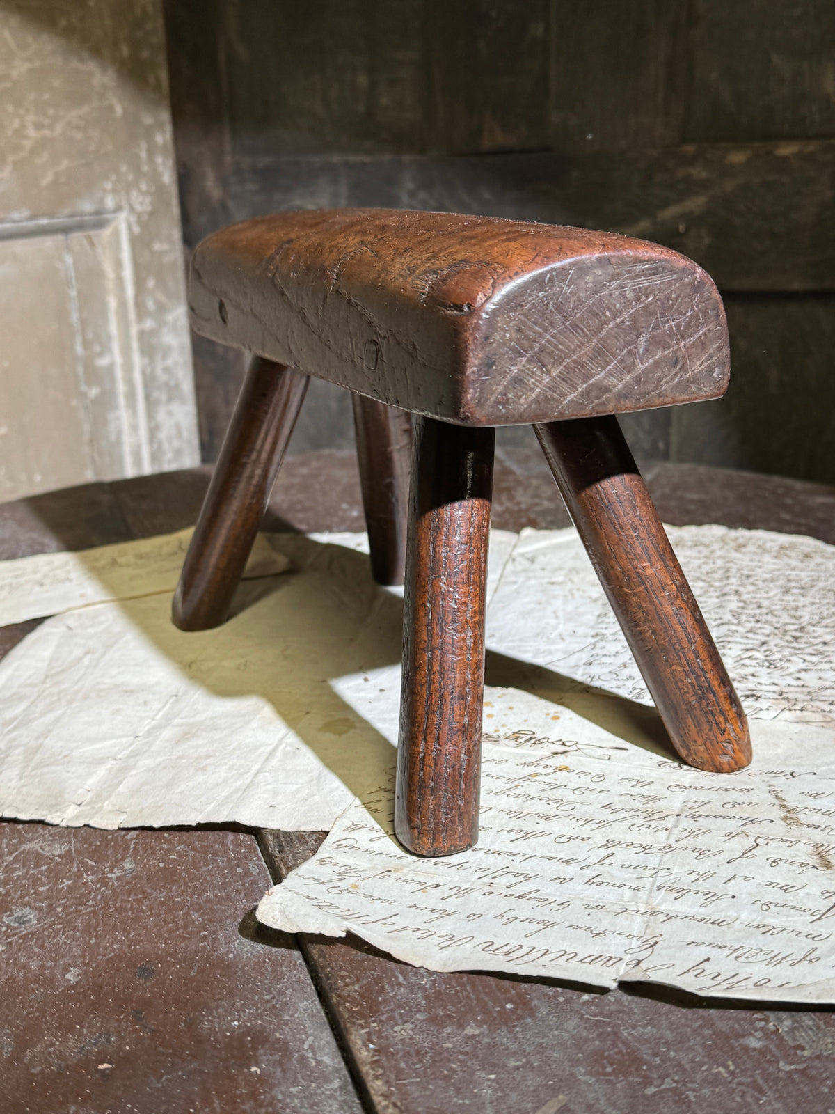 An unusual diminutive vernacular stool with sculpted rounded seat c.1800