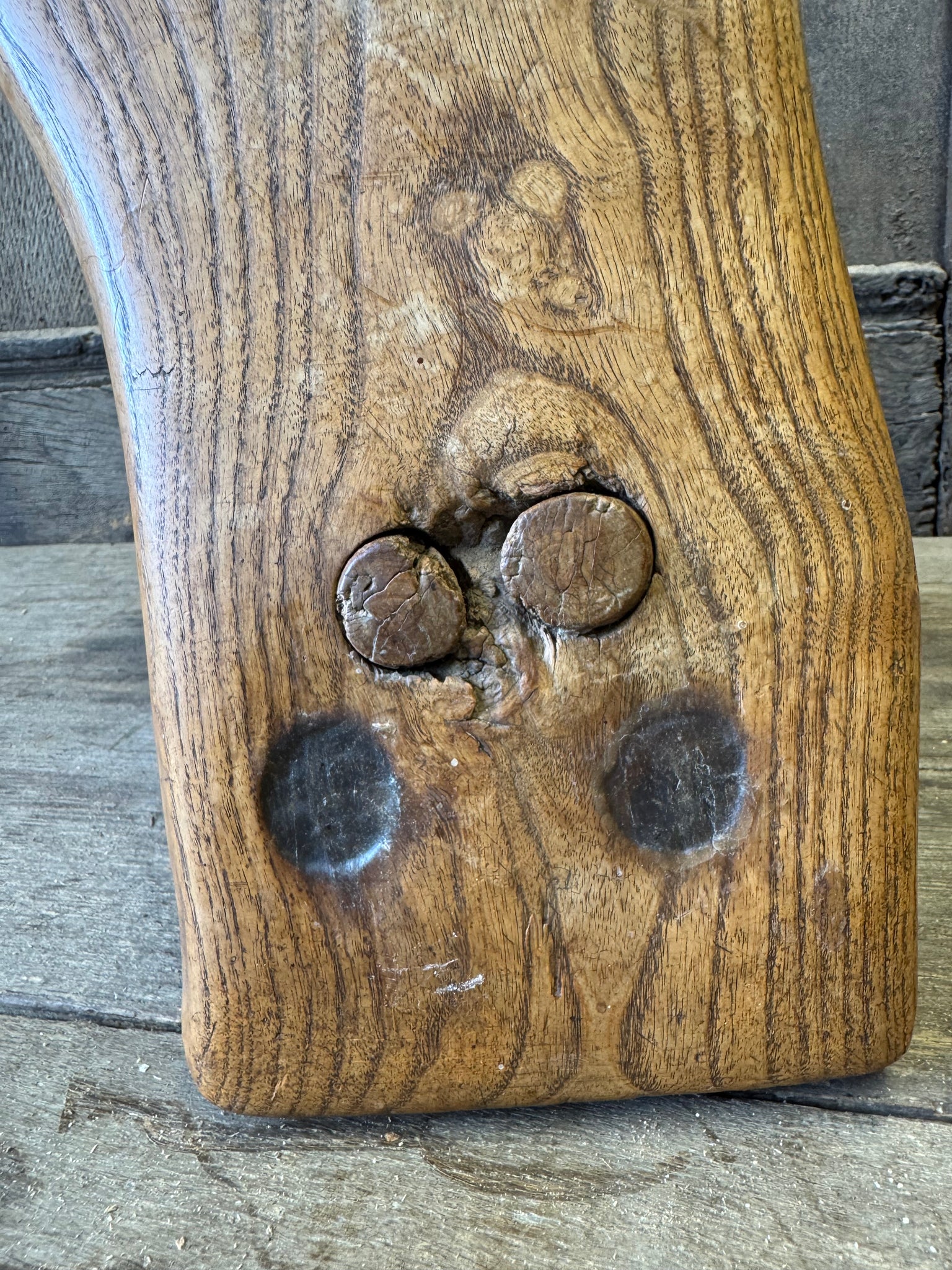 An 18th century elm slab top stool standing over three legs