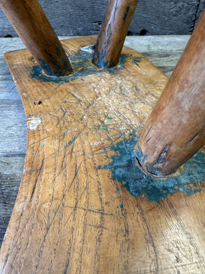 An 18th century elm slab top stool standing over three legs