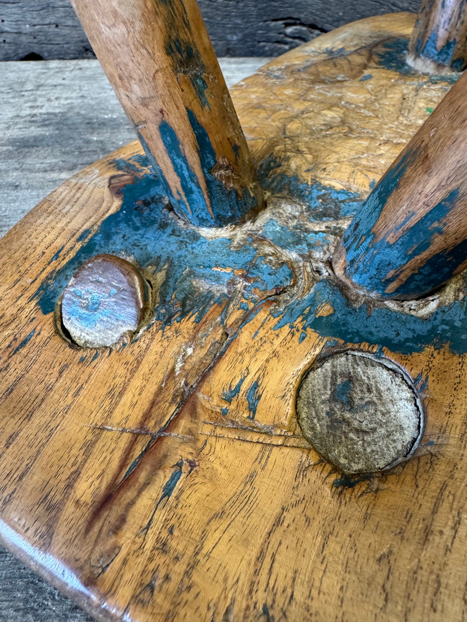 An 18th century elm slab top stool standing over three legs