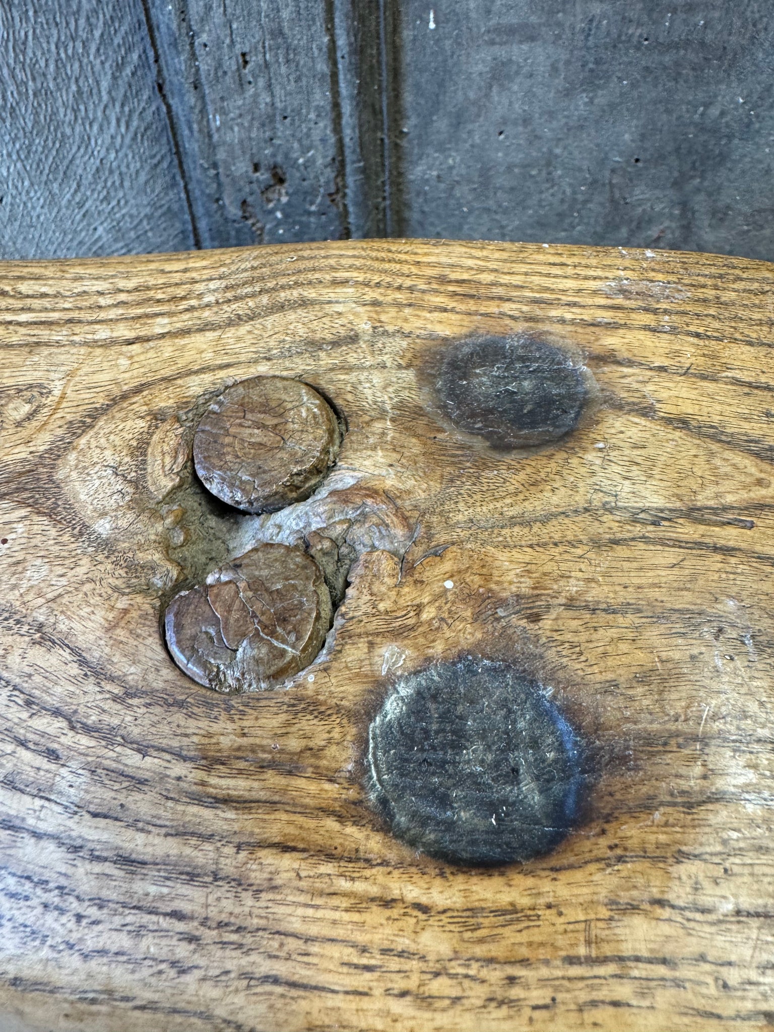 An 18th century elm slab top stool standing over three legs