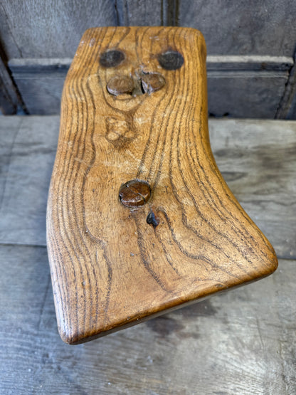 An 18th century elm slab top stool standing over three legs