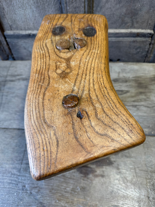 An 18th century elm slab top stool standing over three legs