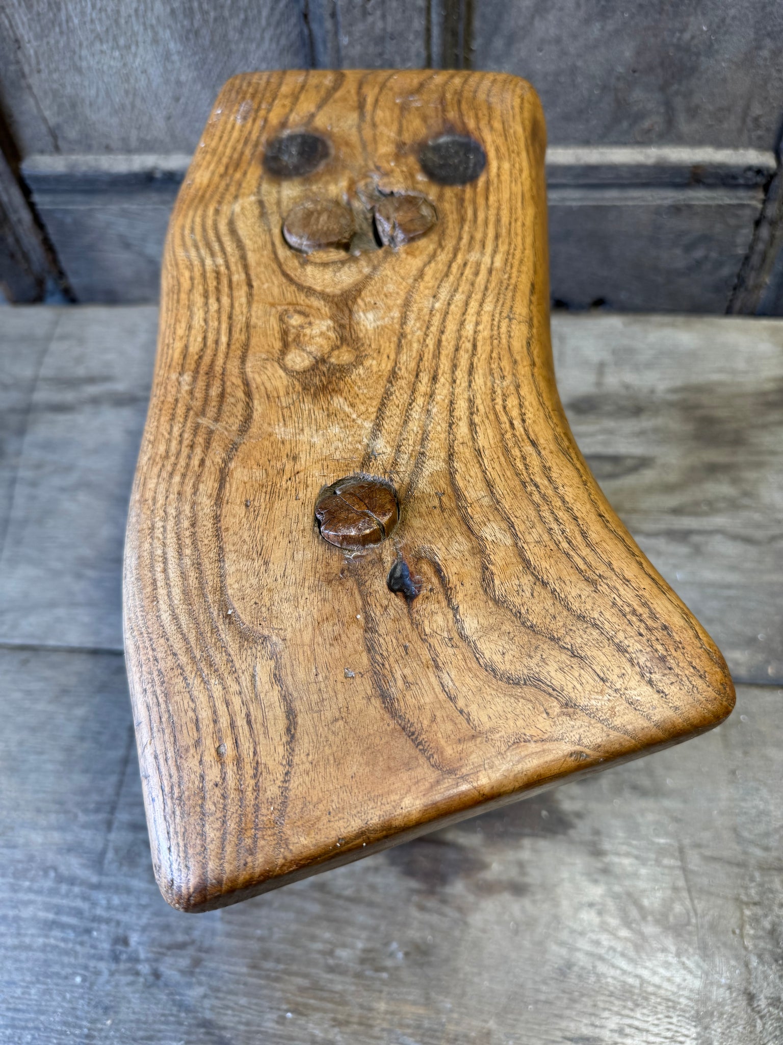 An 18th century elm slab top stool standing over three legs