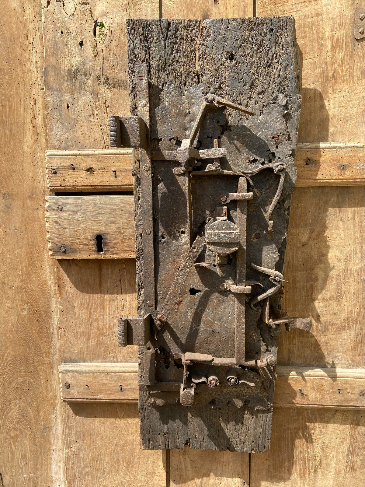 A large sculptural 17th century lock mounted on an oak board
