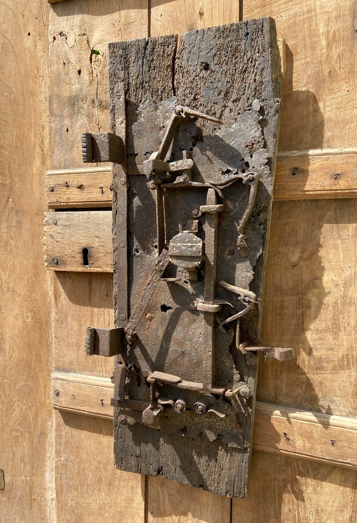 A large sculptural 17th century lock mounted on an oak board