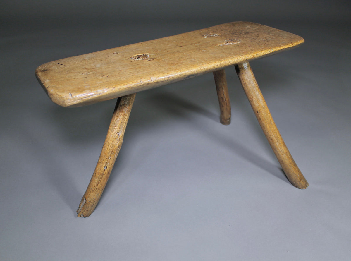 A fine example of a primitive early 19th c three legged sycamore stool