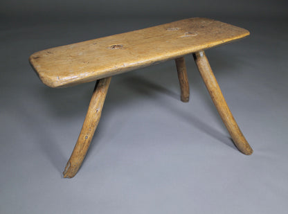A fine example of a primitive early 19th c three legged sycamore stool
