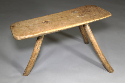 A fine example of a primitive early 19th c three legged sycamore stool
