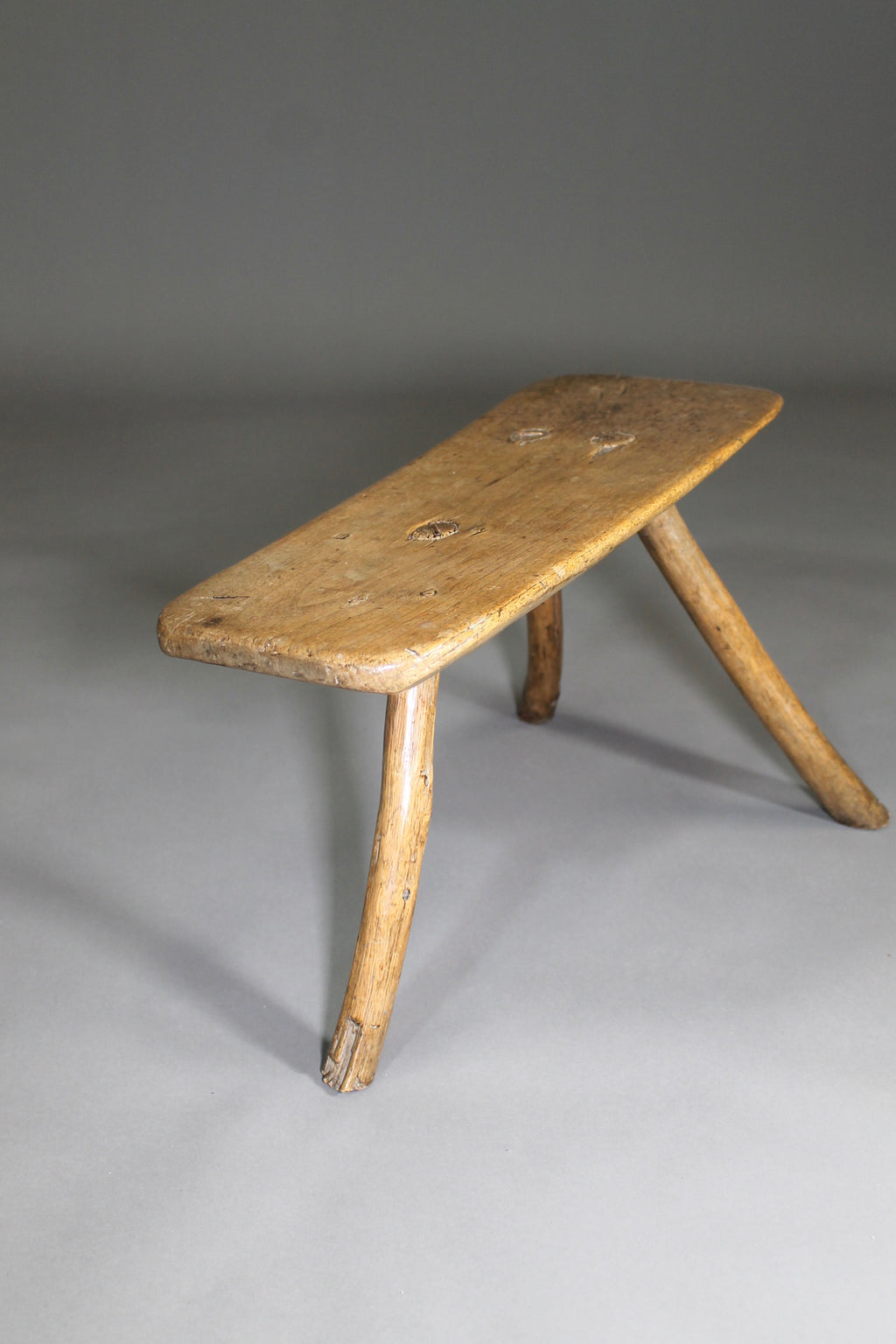 A fine example of a primitive early 19th c three legged sycamore stool