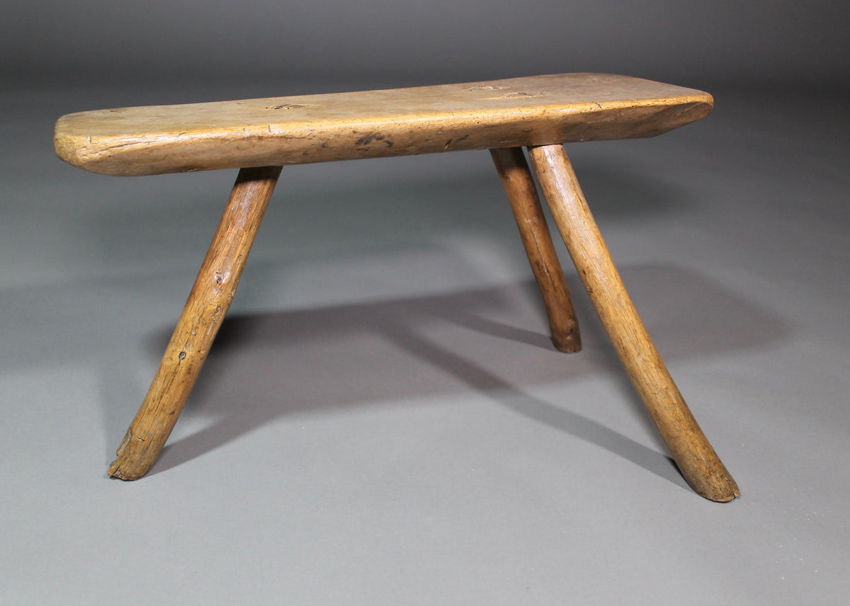 A fine example of a primitive early 19th c three legged sycamore stool